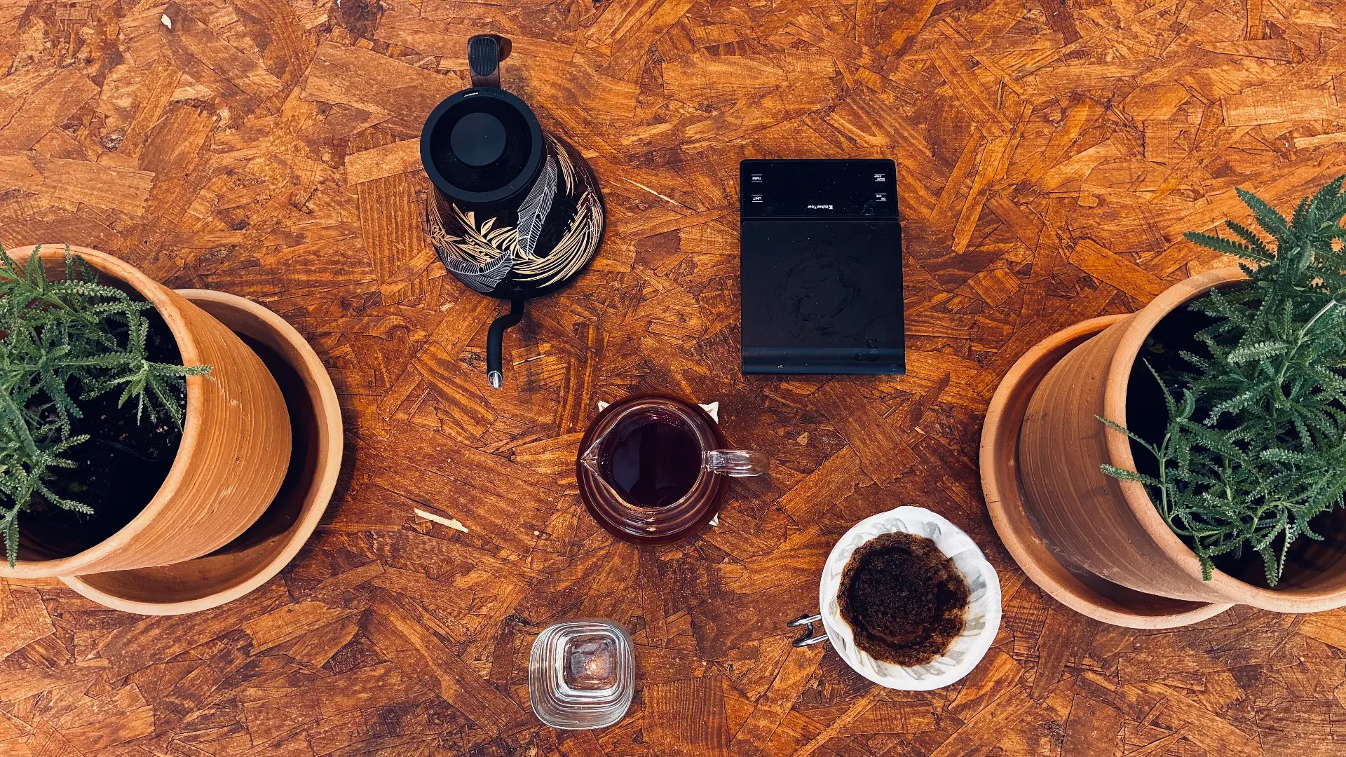 Mesa de madera con V60, jarra de café y plantas de lavanda